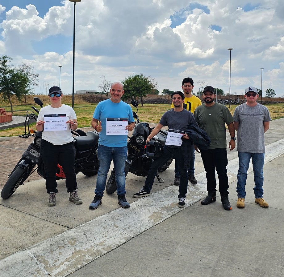 Alumnos de Riding Academy con motocicletas y banner de Legend Garage